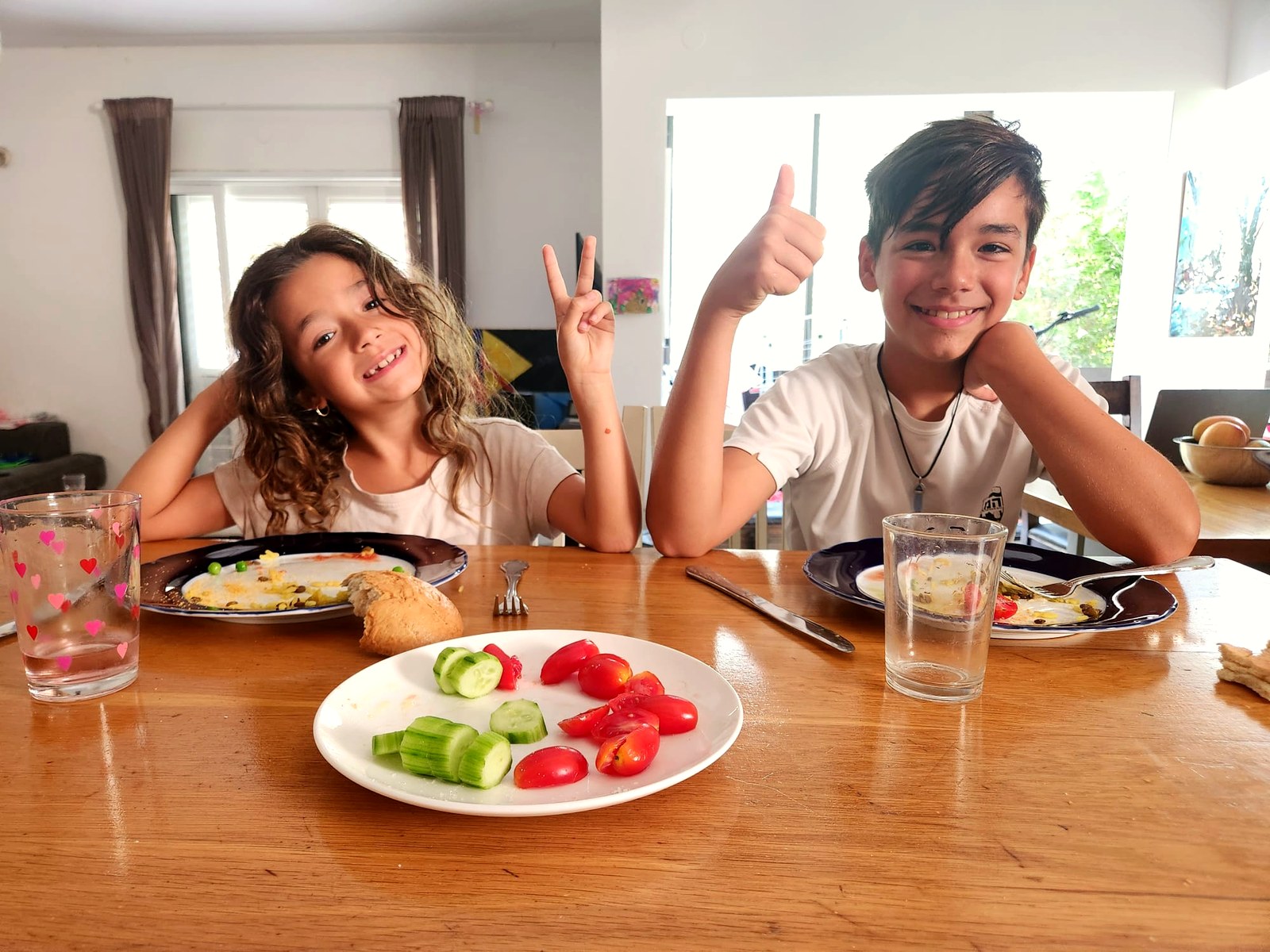 שני ילדים מחייכים אחרי ארוחת צהריים ביתית סביב שולחן המטבח